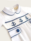 Little Collins Clothing white babygrow with smocking, peter pan collar and blue anchors front view