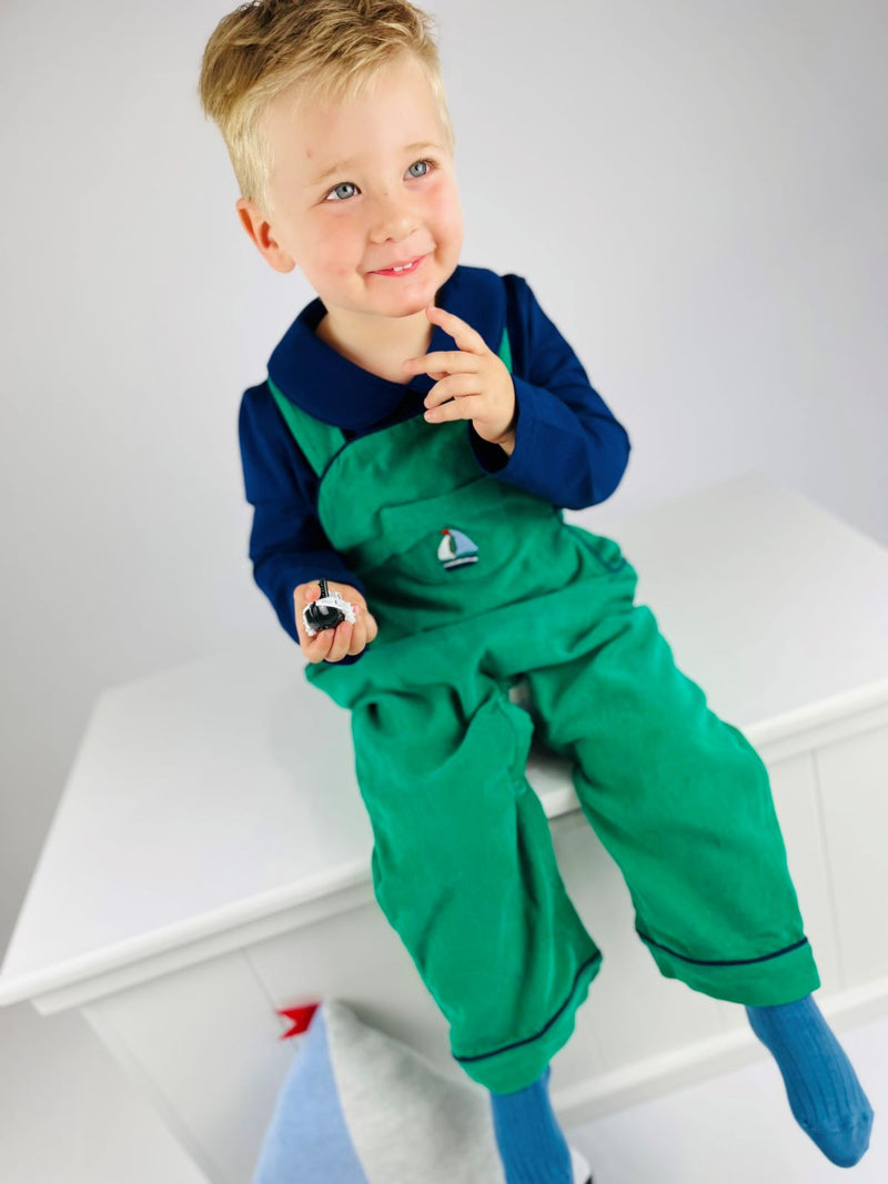 Child wearing green corduroy overalls matched with a blue classic jersey top.