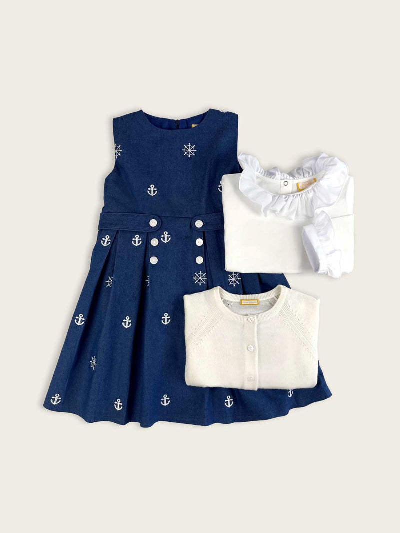 Blue nautical denim girls dress featuring white embroidered anchor and ships wheel motifs paired with winter white cardigan