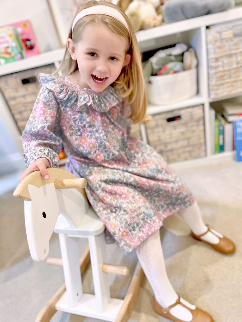 Child wearing the floral children's dress with matching bloomers, featuring a frilled collar with hand smocking.