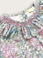 Close up of smocking design stitched into the frilled collar of the floral children's dress.